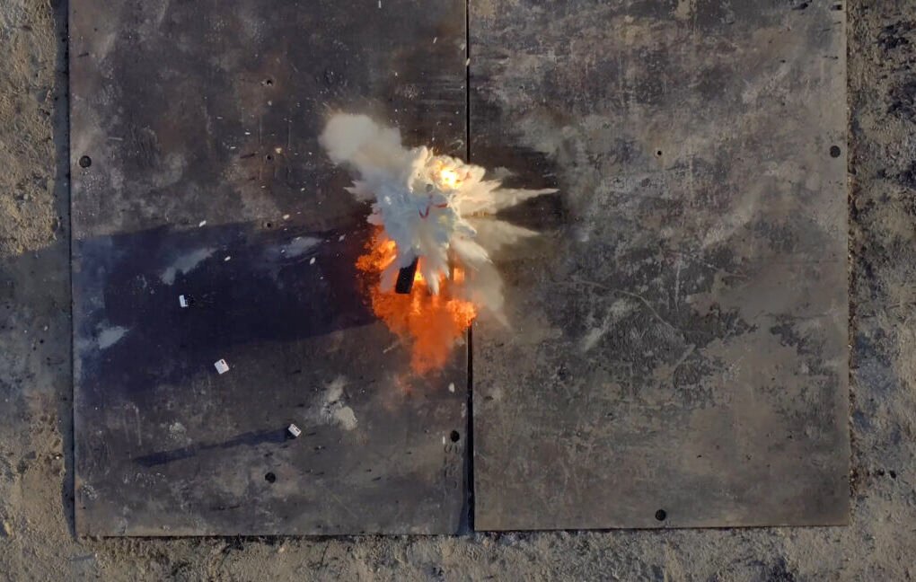 Fire retardant balls dropped by Anduril's Ghost-X drone explode on a fire in a test. The scene from above shows a cloud of fire retardant just spreading out with the blaze beneath it.