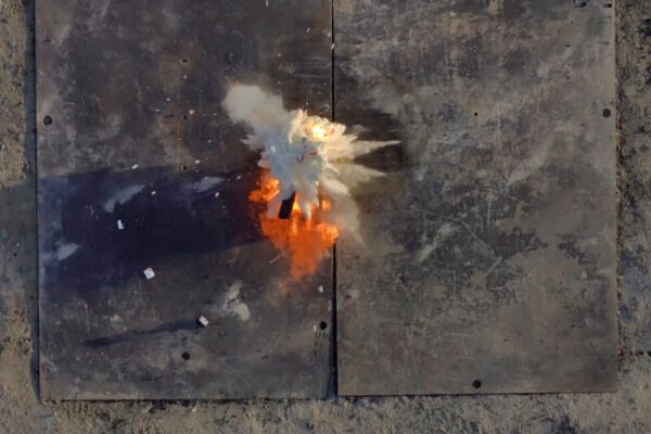 Fire retardant balls dropped by Anduril's Ghost-X drone explode on a fire in a test. The scene from above shows a cloud of fire retardant just spreading out with the blaze beneath it.