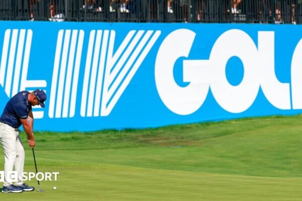 Golfer Bryson DeChambeau putts in front of a big blue and white LIV Golf sign